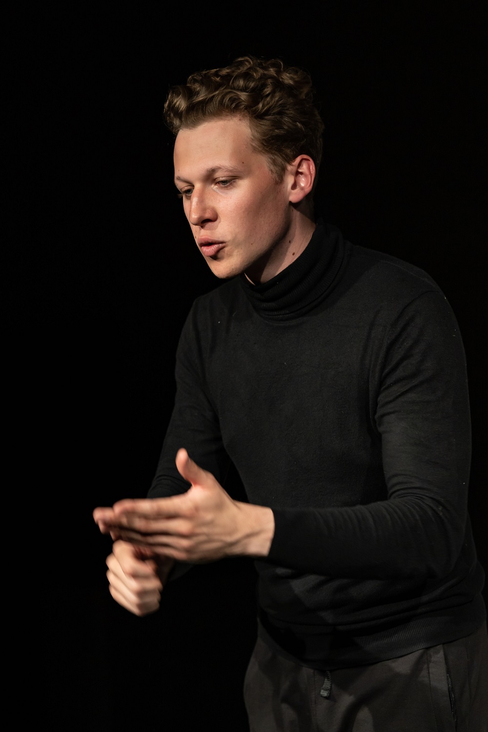 Wojciech Parszewski - młody mężczyzna ubrany w czarny golf żywo gestykuluje.