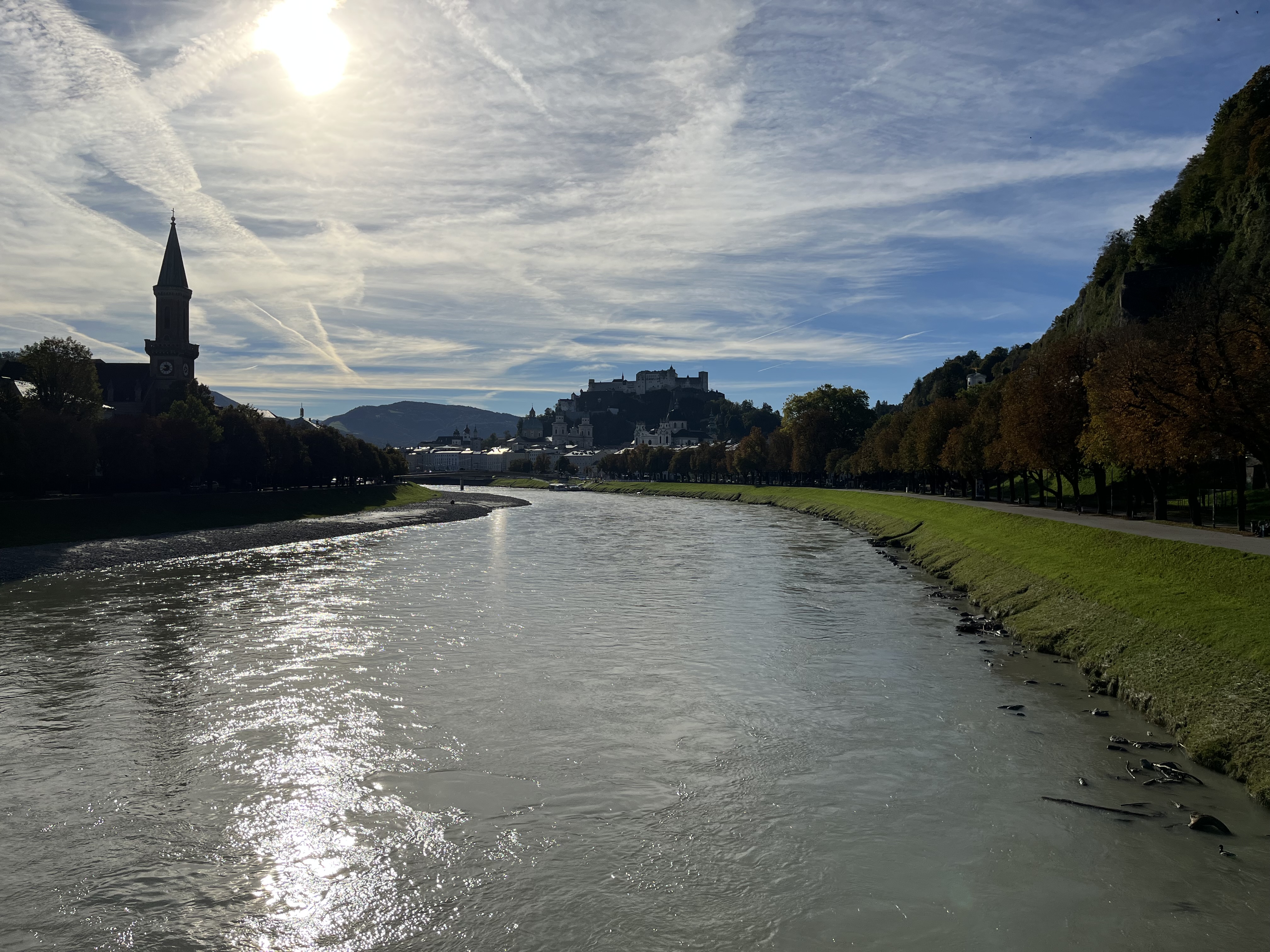 Pejzaż rzeczny, w oddali panorama miasta, na horyzoncie wysoka wieża.