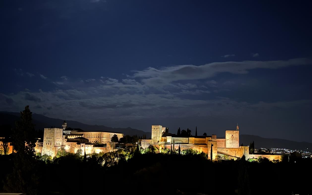 Panoram nocna, widok na oświetlony pałac Alhambra.